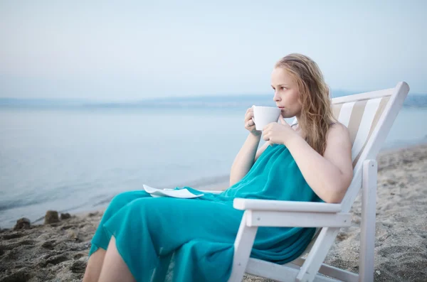 Женщина, наслаждающаяся чашкой чая на берегу моря — стоковое фото