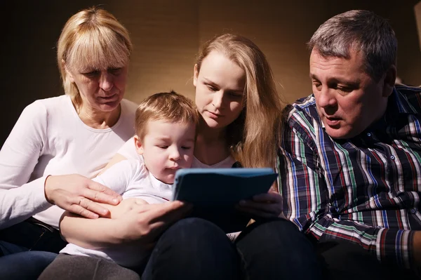 Rodinné sledují chlapce hrát hru na touchpadu — Stock fotografie