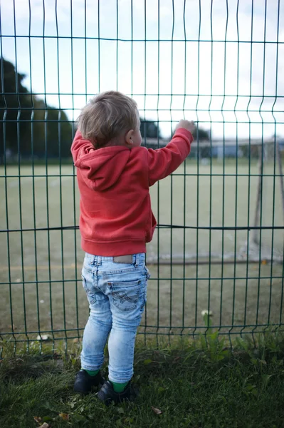 Malý kluk koukal přes drátěný plot — Stock fotografie