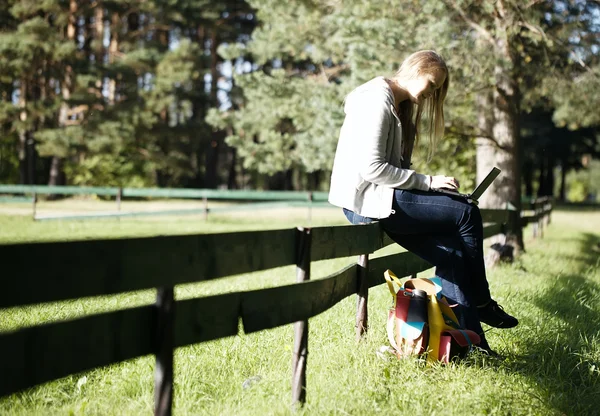 Νεαρή γυναίκα που καθόταν σε ένα ρουστίκ φράχτη — Φωτογραφία Αρχείου