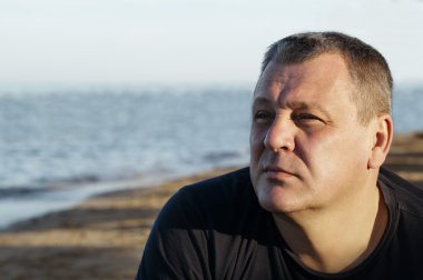 yakışıklı bir orta yaşlı adam sahilde düşünme