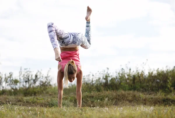 Agile junge Frau beim Handstand — Stockfoto