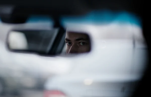 Man looking in the rear view mirror while driving — Stock Photo, Image