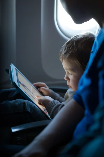 Мальчик играет с планшетом в самолете — стоковое фото