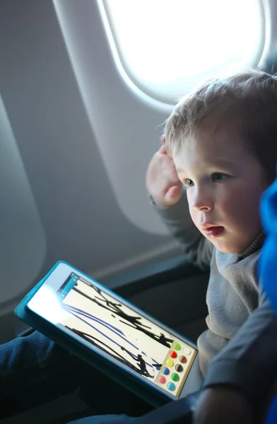 Kleine jongen tekenen op een Tablet PC in een vliegtuig — Stockfoto