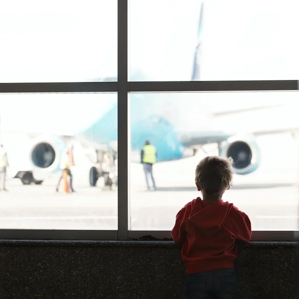 Rapaz olha para o avião no aeroporto — Fotografia de Stock