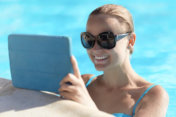 Ung kvinna i en pool med hjälp av tablet PC — Stockfoto