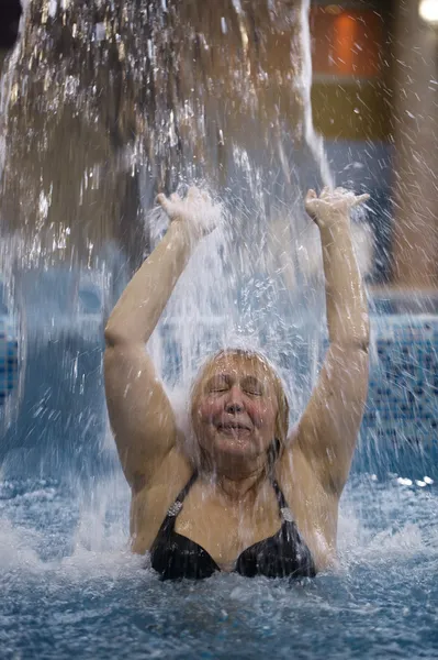 Kobieta pryskającą wodą w basenie pod strumieniem wody — Zdjęcie stockowe