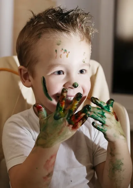 Возбужденный мальчик играет с красками для пальцев — стоковое фото
