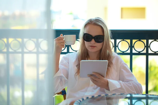 Mujer sentada leyendo una tableta-PC en el balcón —  Fotos de Stock