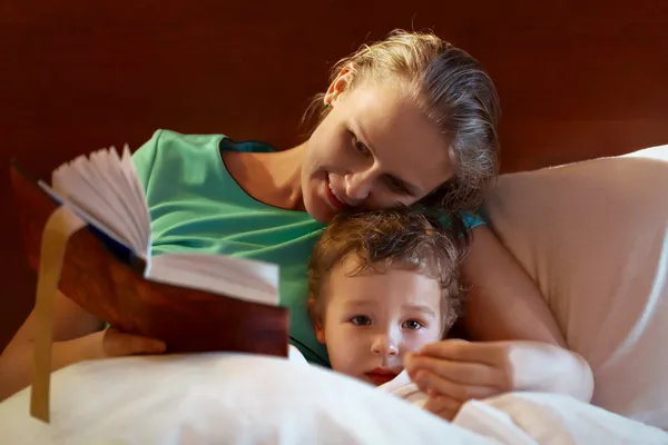 Joven madre leyendo a su hijo en la cama — Foto de Stock
