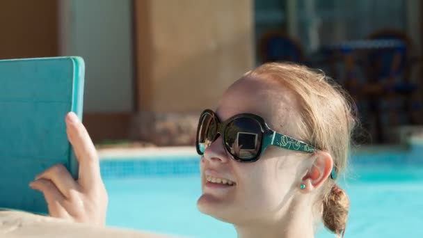 Jovem mulher usando um comprimido à beira da piscina — Vídeo de Stock