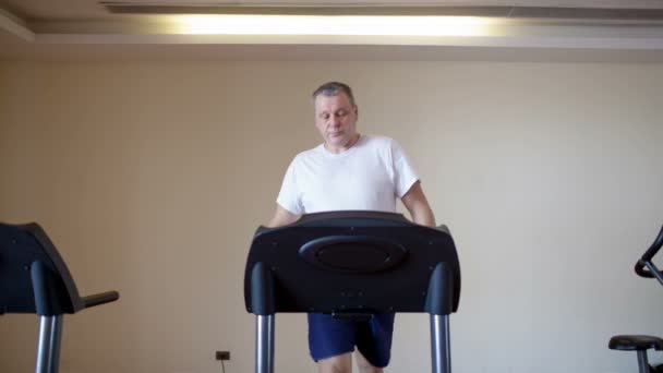 Mann mittleren Alters trainiert auf einem Laufband — Stockvideo