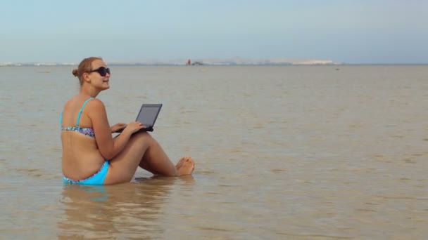 Femme utilisant un ordinateur portable assis dans la mer — Video