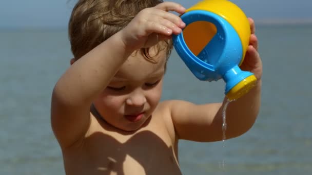 Menino se divertindo com pote de água de brinquedo — Vídeo de Stock
