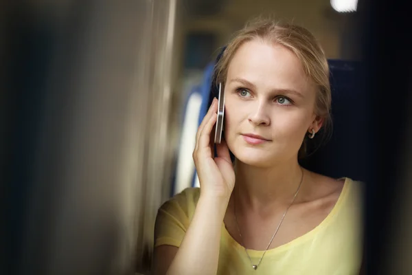 Молодая женщина слушает свой мобильный во время поездки на поезде — стоковое фото