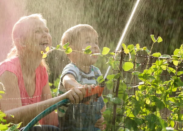 Moeder en haar jonge zoon spelen met water — Stockfoto