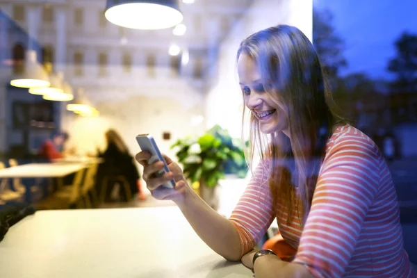 Jovem mulher sentada em um restaurante usando um celular — Fotografia de Stock