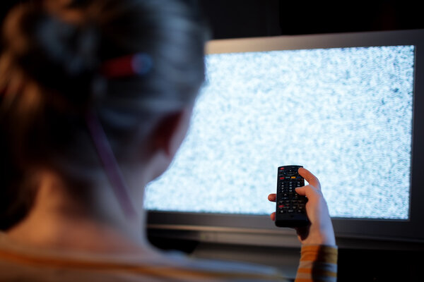 Woman with remote control in front of TV set