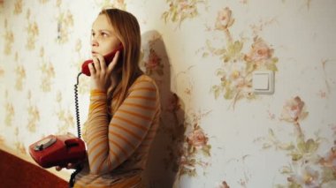 Genç bir kadın evde telefonla konuşuyor.