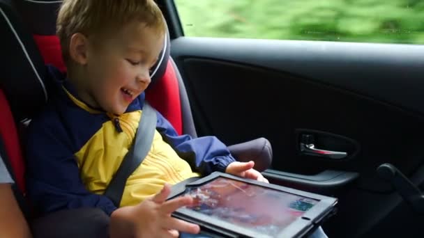 Little boy playing on tablet computer in the car — Stock Video