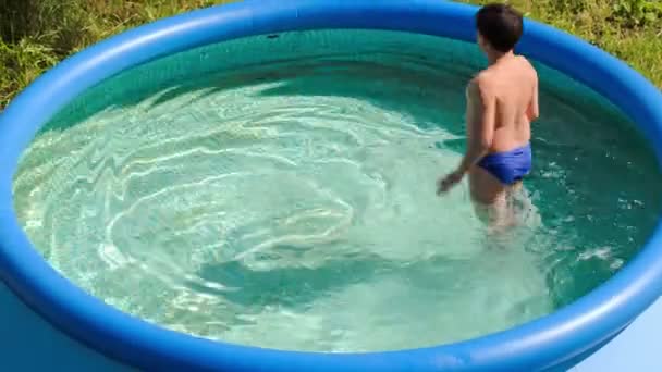 Chico divirtiéndose en piscina al aire libre en un día caluroso de verano — Vídeos de Stock
