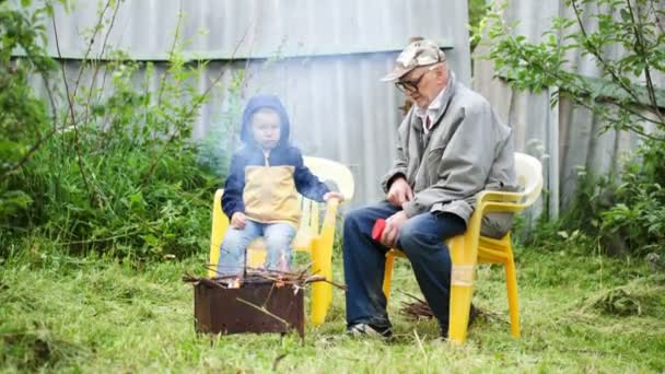 Nonno e nipote seduti accanto al fuoco — Video Stock