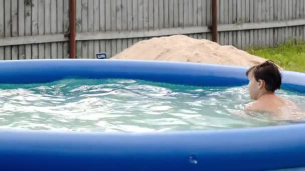 Boy swimming in inflatable pool in the yard — Stock Video