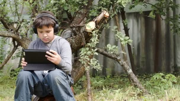 Adolescente em fones de ouvido usando touchpad ao ar livre — Vídeo de Stock
