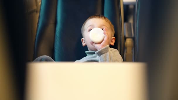 Мальчик в поезде пьет молоко из бутылки — стоковое видео