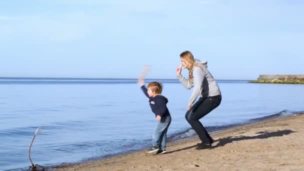 Moeder en zoon gooien houten stukken in het water — Stockvideo