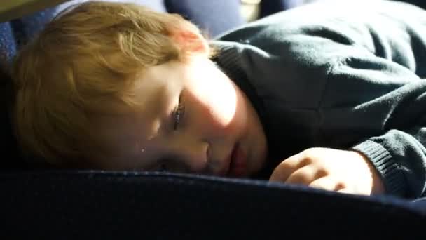 Kleine jongen liggend op de zetel in de trein — Stockvideo