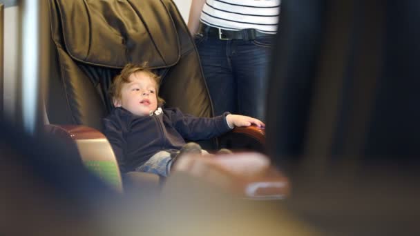 Niño pequeño sentado en silla de masaje — Vídeos de Stock