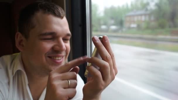 Молодой человек печатает смс в движущемся поезде — стоковое видео