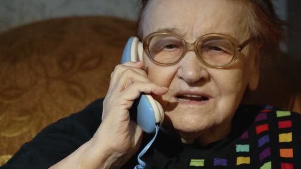 Пожилая женщина в очках отвечает на звонок — стоковое видео
