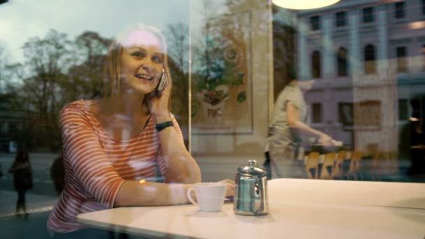 Жінка розмовляє мобільним телефоном у кафе — стокове відео