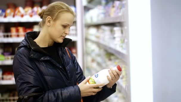 Жінка кладе молоко в кошик для покупок — стокове відео