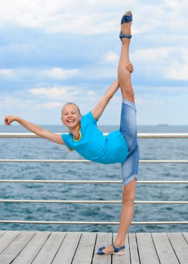 Smiling girl making stretching exercise by the sea clipart