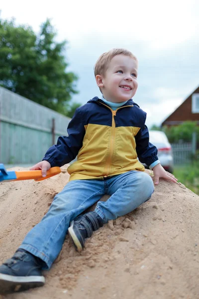 Šťastný chlapeček sedí na písečném kopci — Stock fotografie