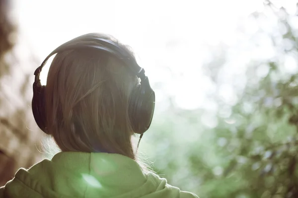 Woman in headphones against bright sunlight — Stock Photo, Image