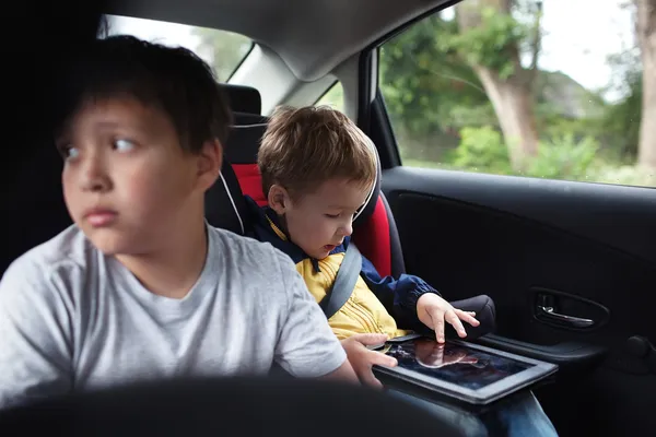 Two boys traveling on the back seat of a car — Stock Photo, Image