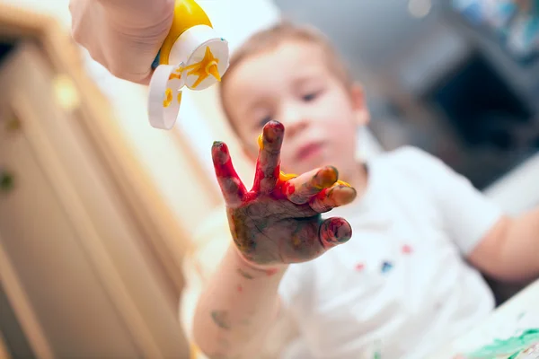 Pressing finger-paint on boys hand — Stock Photo, Image