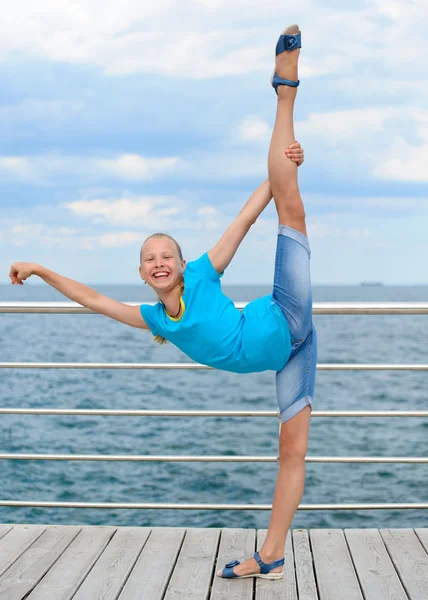 Smiling girl making stretching exercise by the sea — Stock Photo, Image