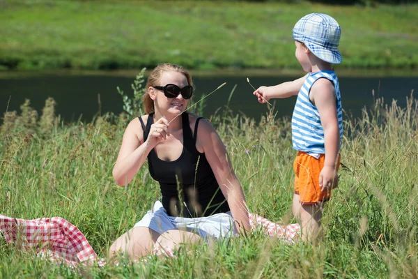 Mother and son playing with grass on the meadow — Stock Photo, Image