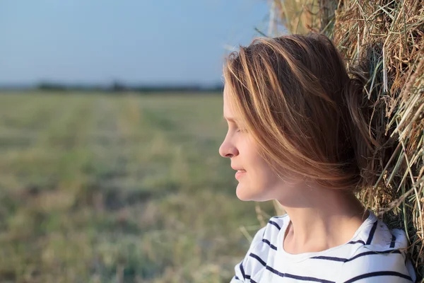 Relaxed woman near hay roll in the field — Stock Photo, Image