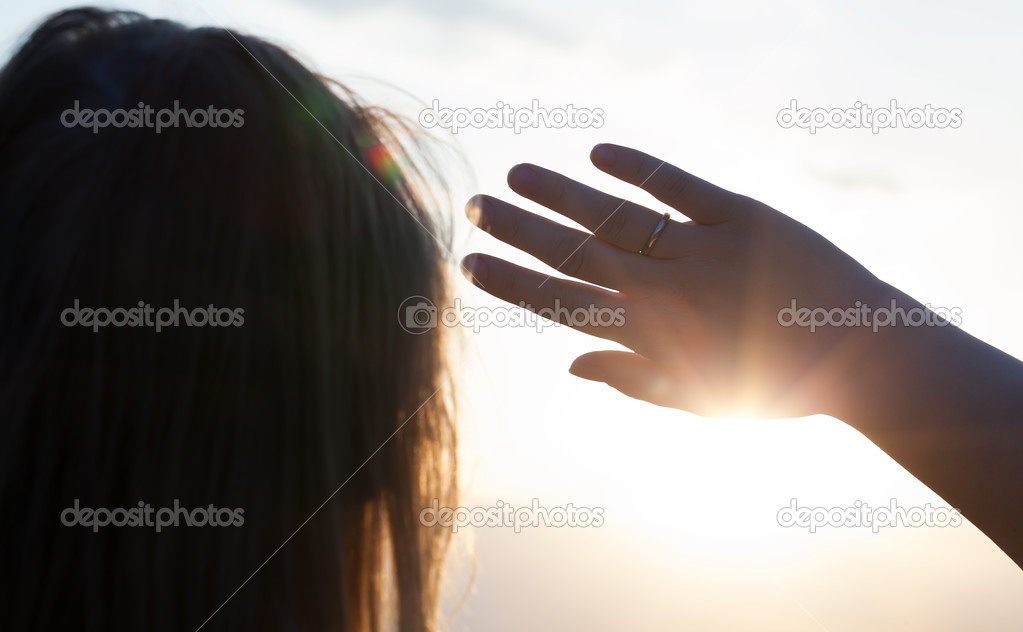 Woman hiding from the sun with hand