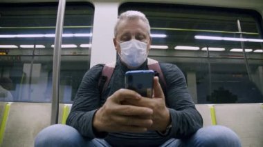 Metro vagonunda koruyucu maskeli bir adam.