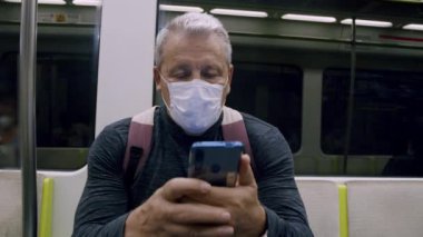 Metroda akıllı telefonu olan bir adam.