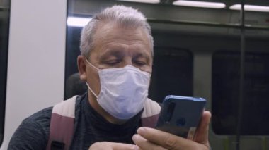Metroda cep telefonu kullanan yaşlı bir banliyö.