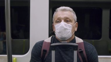 Metroyla seyahat eden maskeli adam.